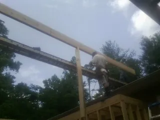 Carpenter setting a ridge beam over a new addition frame — Ice Dam Removal by Roofing Brothers in Lake Odessa