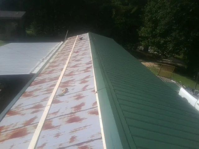 Old rusted panels beside newly installed green metal roofing — Wind Damage Roof Repair by Roofing Brothers in Lake Odessa