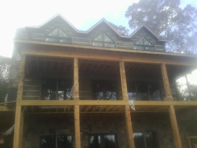 Dormers and porch framing on a large log home under construction — Roof Coating work by our crew in Lake Odessa