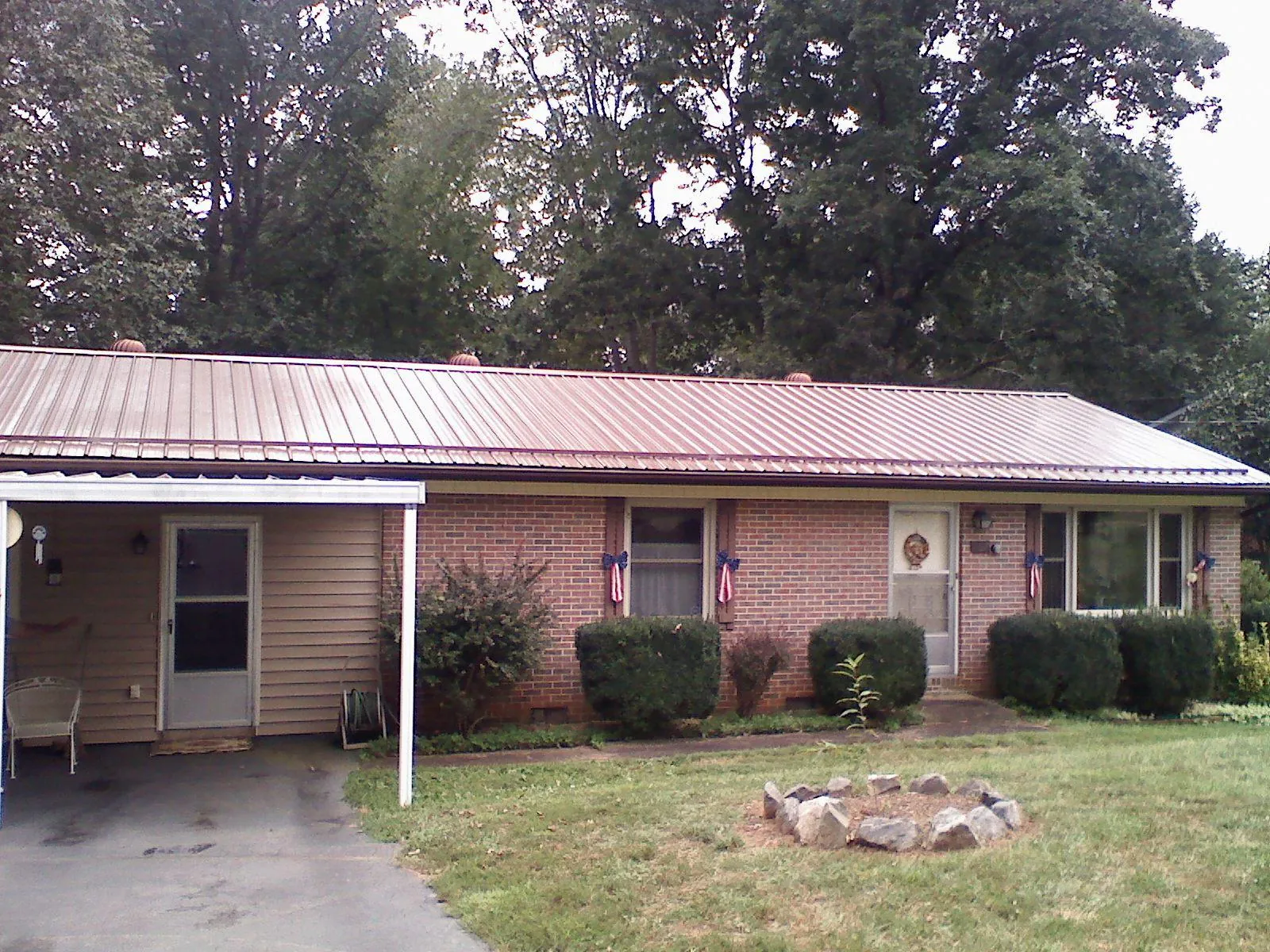 Bronze metal roof and carport on a brick ranch home — Roof Repair work by our crew in Lake Odessa