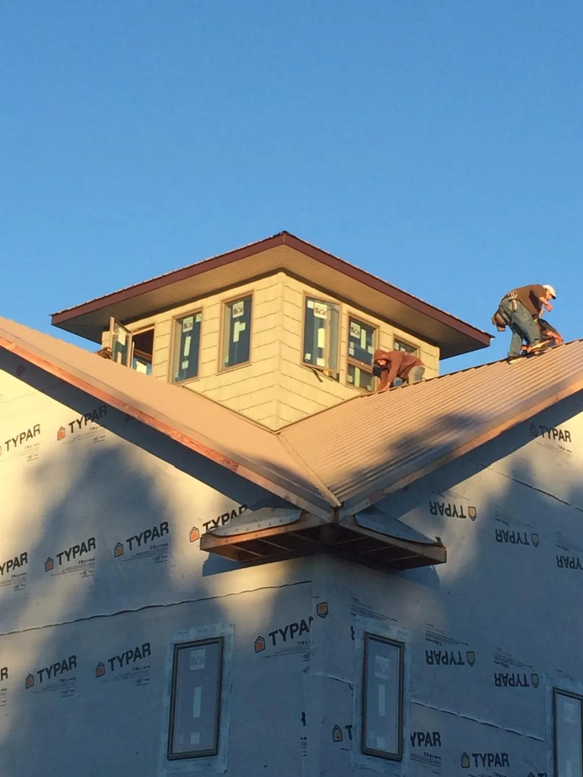 Roofers working around a rooftop cupola on a new metal roof at sunset — Roof Waterproofing in Lake Odessa by Roofing Brothers